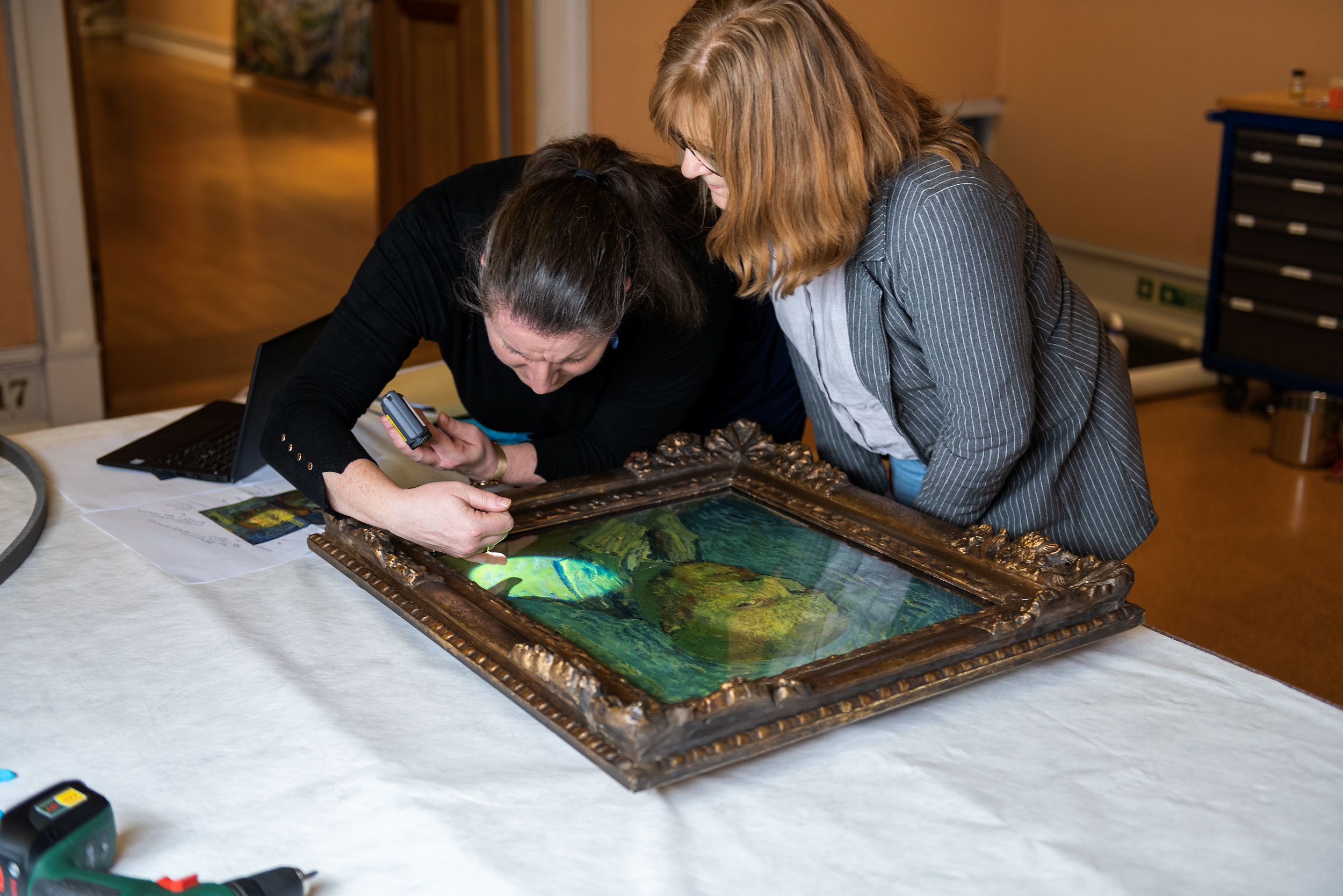 Maleriet rutinesjekkes av konservator før det lånes ut til Van Gogh-museet i Amsterdam. Konservator står over maleriet med lykt