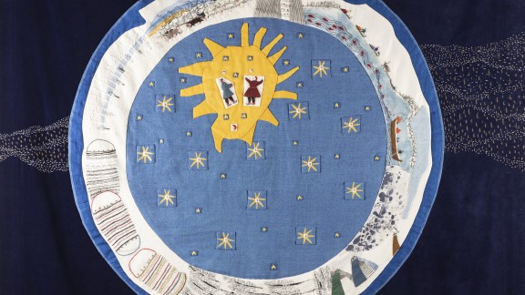 En blå sirkel, omgitt av en hvit sirkel, på en bakgrunn med en brodert illustrasjon av Melkeveien