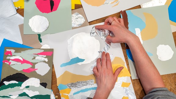 Nærbilde av hender som arbeider med collage i papir og metallfolie.